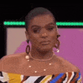 a woman wearing earrings and a necklace is making a face .