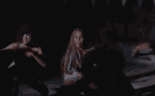 a woman with braids is standing in a dark room with a sword in her hand .