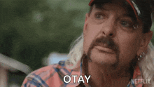 a man with a ponytail and a hat is making a face and saying okay .
