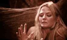 a woman with a bloody face is sitting next to a tree .