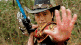 a man in a cowboy hat is holding a blue sword .