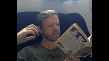 a man sitting on a couch reading a book with a barcode on the back