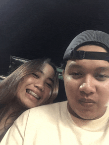 a woman with braces smiles next to a man wearing a hat that says vans