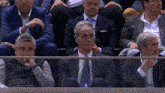 a man in a suit and tie sits in the stands