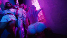 a group of women are dancing in a room with purple lights