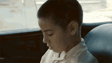 a young boy is sitting in the back seat of a car with his eyes closed .