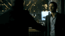 two men are standing next to each other in a dark room .