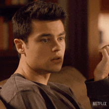 a man is sitting on a couch with a netflix logo on the bottom right