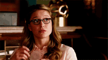 a woman wearing glasses and a pink shirt is eating something