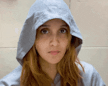a woman wearing a gray hoodie looks at the camera