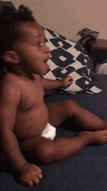 a baby in a diaper sits on a couch