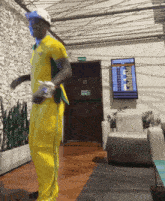 a man in a yellow outfit is dancing in a room with a sign that says ' avenida ' on it