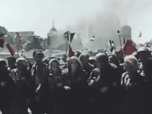 a large group of people are standing in front of a building with smoke coming out of it .