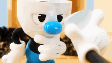 a cartoon character with a blue nose is holding a cup in his hand