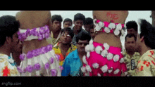 a group of people are standing around a woman in a pink dress with flowers around her waist .