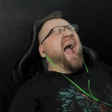 a man with glasses is laying down with his mouth open and his tongue sticking out