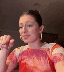 a woman wearing a red shirt and hoop earrings is giving a thumbs down sign .