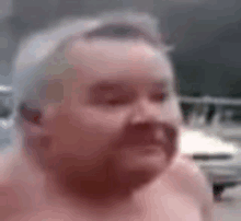 a shirtless man with a mustache is smiling in a blurry photo .