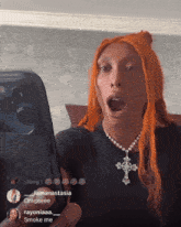 a woman with orange hair is holding a cell phone in front of her