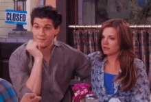 a man and a woman are sitting in front of a closed sign