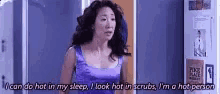 a woman in a purple tank top is standing in front of a door and talking .