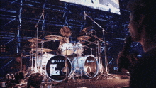 a man is holding a microphone in front of a drum set that says saka on it
