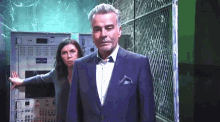 a man in a suit and tie is standing next to a woman in a blue shirt