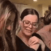 a woman wearing glasses is standing next to another woman .