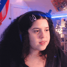 a woman wearing headphones looks at the camera with a sign behind her that says c-naga on it