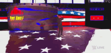 kurt angle is standing in front of an american flag in a wrestling ring