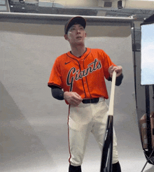 a man in a giants jersey holds a bat
