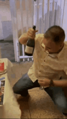 a man is kneeling down holding a bottle of wine