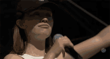 a woman wearing a white tank top and a black hat with the letter s on it