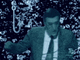 a man in a suit and tie is standing in front of a hook that says r on it