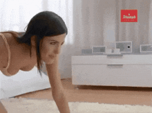a woman in a bra is crawling on the floor in front of a sign that says triumph