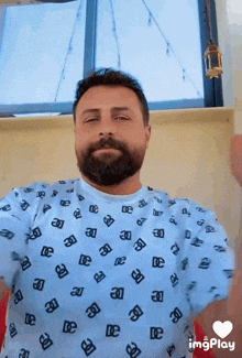a man with a beard is wearing a blue shirt with black letters on it