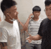 a group of young men are standing next to each other and one of them is wearing a face mask .