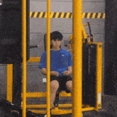 a man in a blue adidas shirt is sitting on a machine