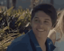 a man in a blue shirt is smiling and looking at the camera while standing next to a woman .