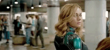 a woman in a green and black superhero costume is standing in a crowded area .