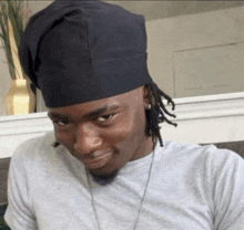 a man with dreadlocks wearing a black hat and a gray shirt