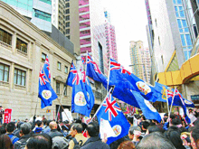 a crowd of people holding blue flags in front of a building that says bank of china