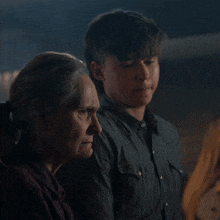 a boy and an older woman are standing next to each other in a dark room