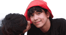 a man in a red hat is kissing another man 's cheek .