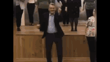 a man in a suit is dancing with a group of people on a stage .
