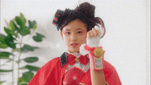 a young girl is wearing a red cape and boxing gloves and making a funny face .