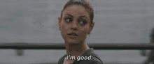 a woman is standing in front of a window and saying i 'm good .