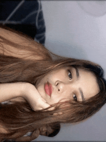 a woman with long hair is laying down with her head resting on her hand