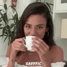 a woman is drinking a cup of coffee and the word safffic is on the bottom .