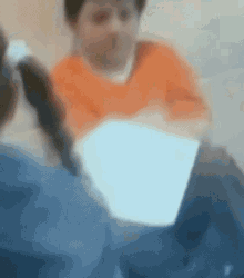 a blurry picture of a man in an orange shirt holding a piece of paper